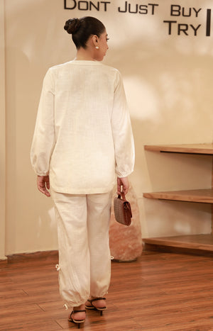 Back view of an off-white long-sleeve cotton tunic and relaxed trousers.