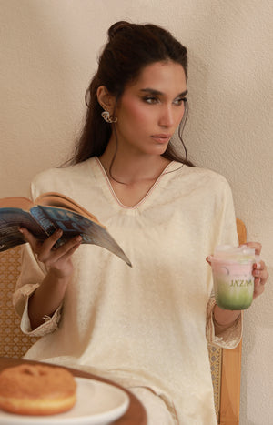Close-up of an off-white V-neck tunic featuring subtle embroidered neckline and sleeve details.