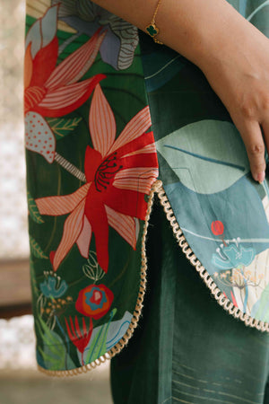 Close-up of a green fabric with floral embroidery and a hand holding it.