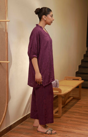 Side profile of the plum purple tunic set highlighting the three-quarter sleeves and wide-leg trousers.
