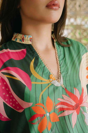Close-up of a person wearing a green floral dress with colorful flowers.

